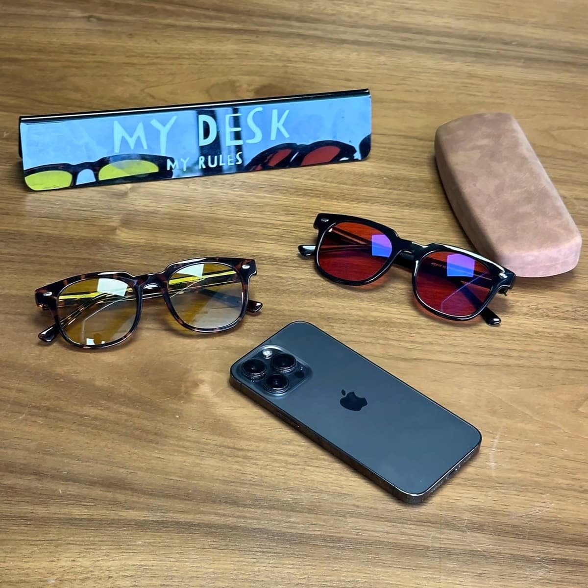 Deux paires de lunettes Bleuvex, un étui et un téléphone posés sur un bureau en bois