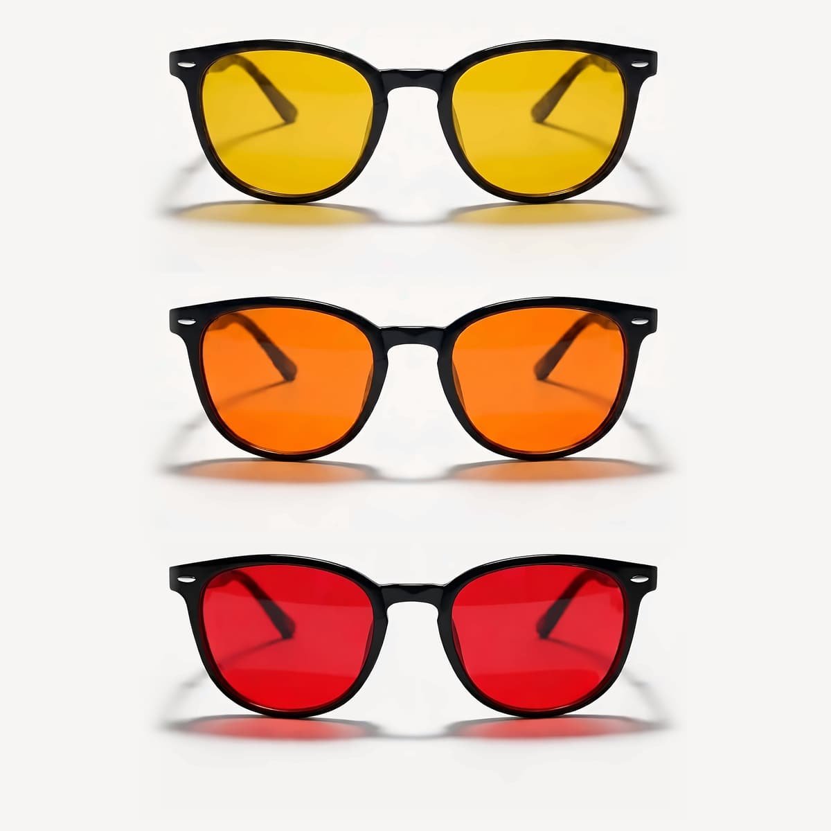Le set Jour → Nuit : lunettes Bleuvex Ambris (jaune), Solaris (orange) et Noctis (rouge) sur fond crème