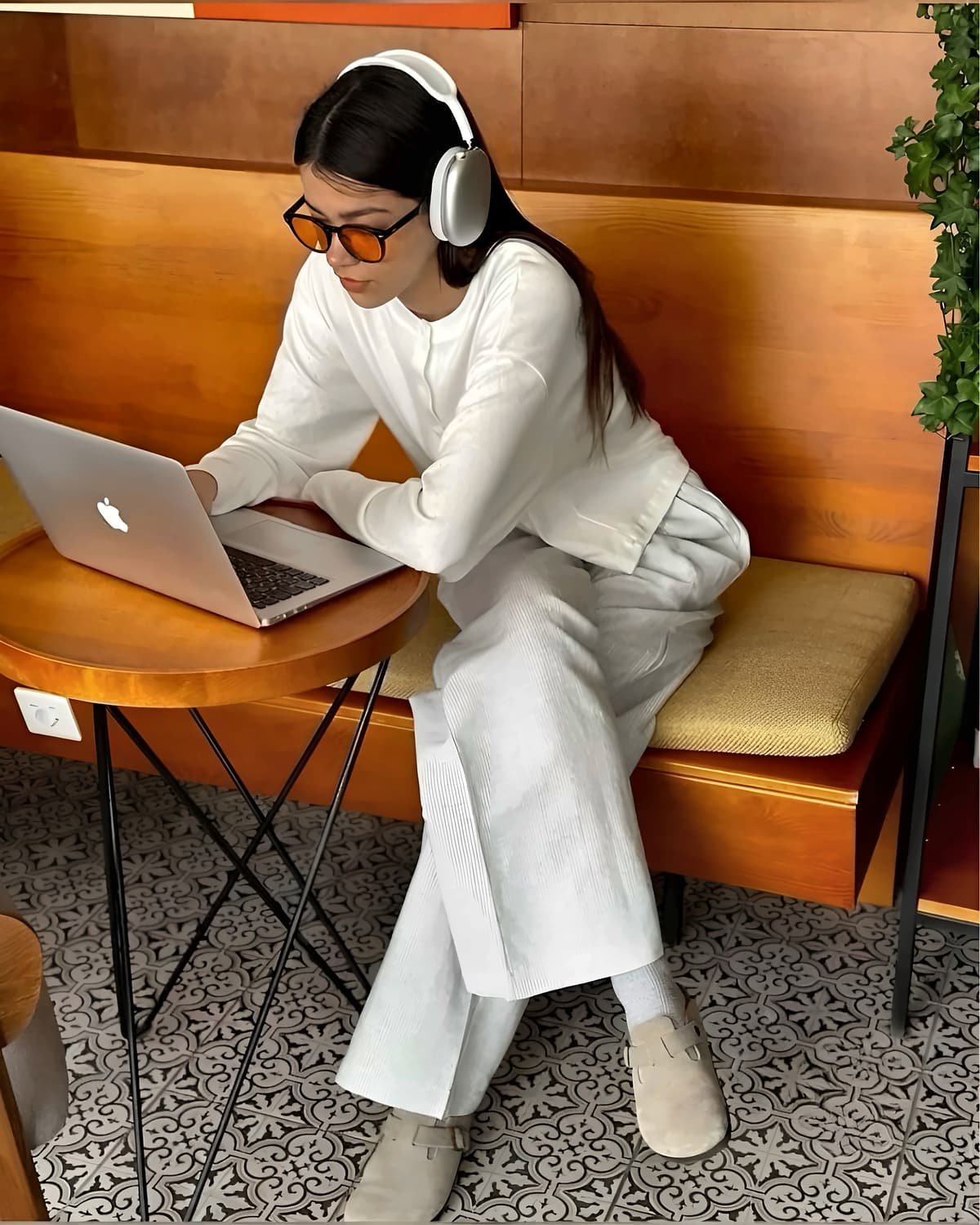 Femme avec un casque, travaillant sur son ordinateur dans un café, portant des lunettes Bleuvex Solaris aux verres orange